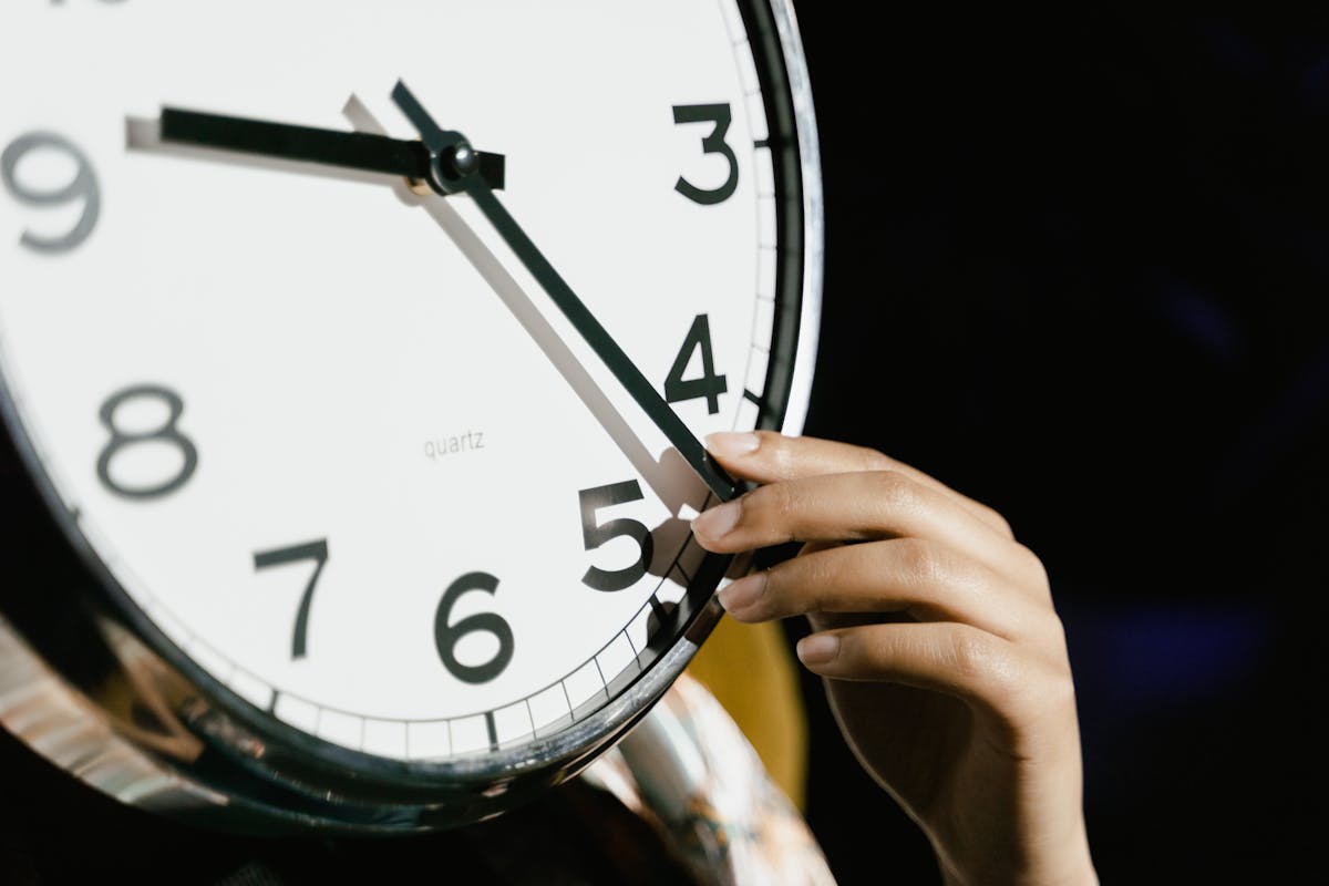 Worker calculating hourly wages with calculator and time clock paperwork on a wooden desk